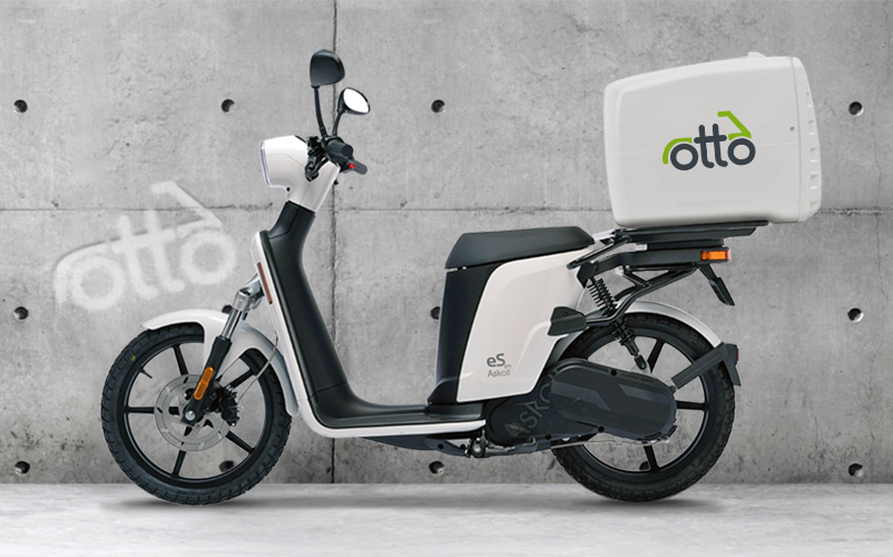 Electric Delivery Scooter With A Large Cargo Box Parked Against A Concrete Wall.
