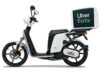 A White Electric Scooter With A Large Uber Eats Delivery Box Mounted On The Back, Perfect For Those Looking To Rent A Scooter In London, Shown From The Side Against A White Background.